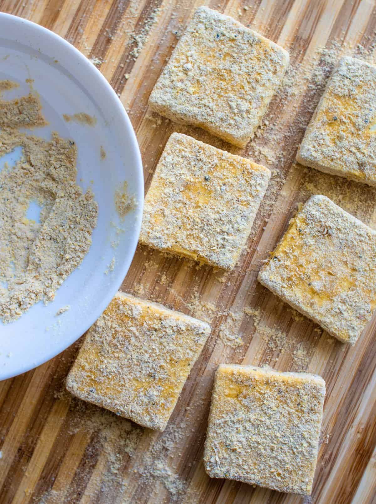 square slices of tofu covered in eggy seasoning, ready to be cooked