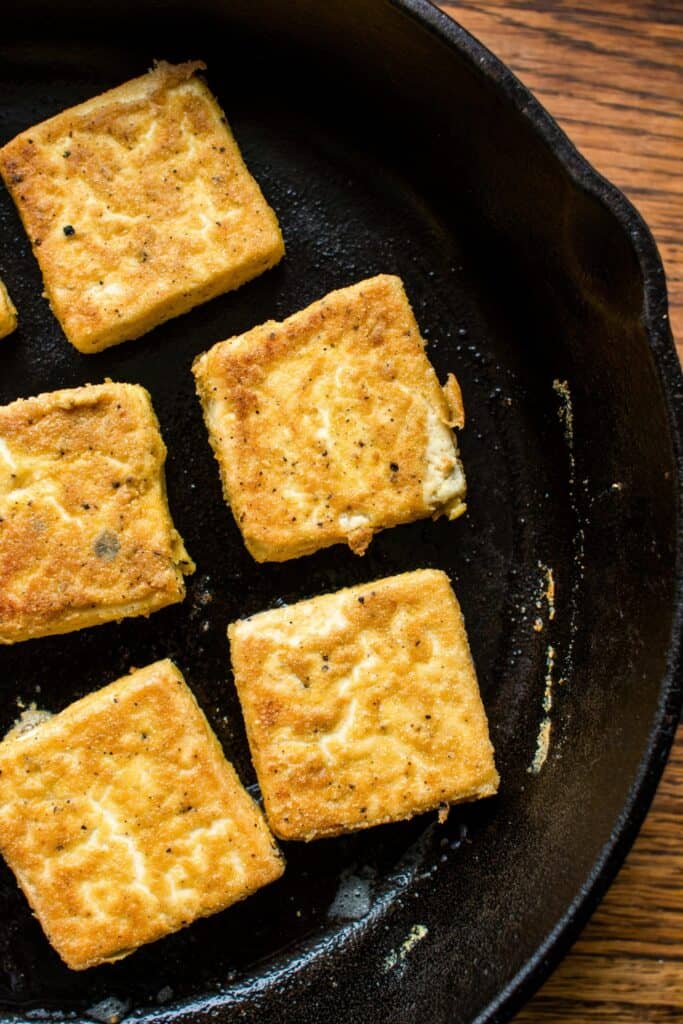 vegan tofu breakfast egg patties cooking in a cast iron pan