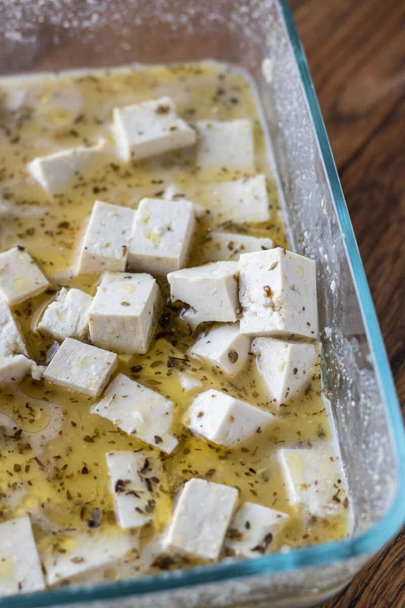 tofu cubes in an herbed marinade in a tupperware container