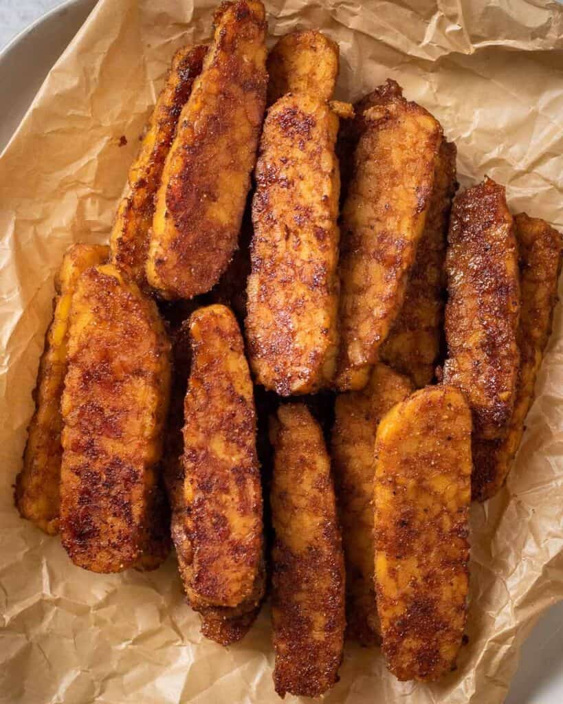 cooked tempeh bacon stacked on a plate