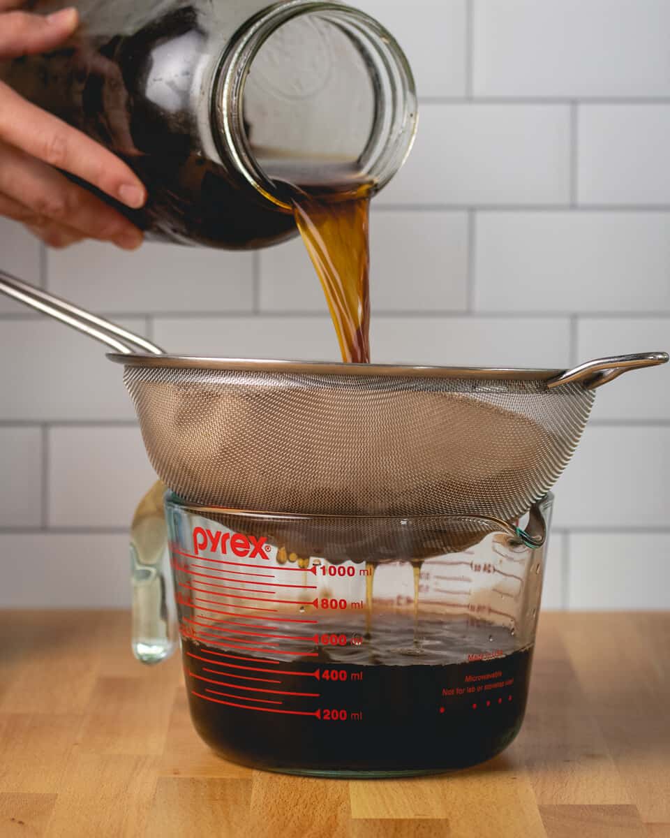 a batch of cold brew being poured through a sieve
