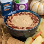 Pumpkin cheesecake dip in a bowl served with homemade graham crackers and apple slices