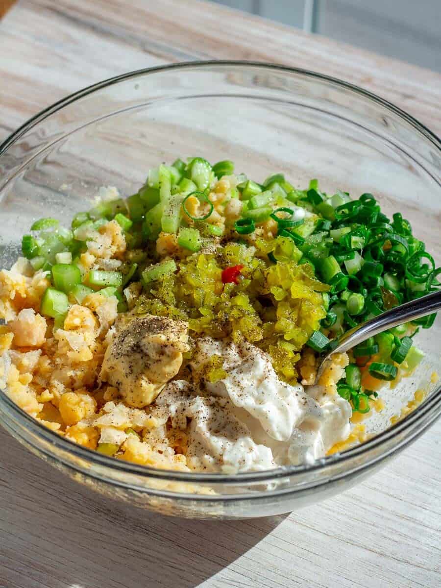 mashed chickpeas in bowl with vegan tuna salad ingredients