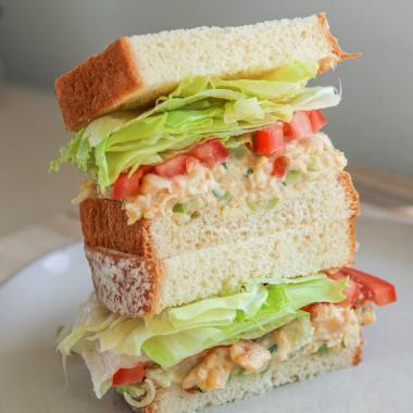 two halves of a vegan chickpea salad sandwich stacked on top of each other, showing the cross section