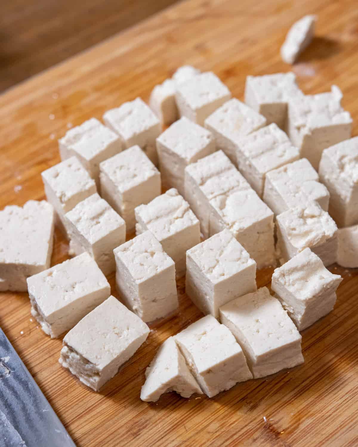 closeup shot of homemade tofu, chopped into cubes on a cutting board