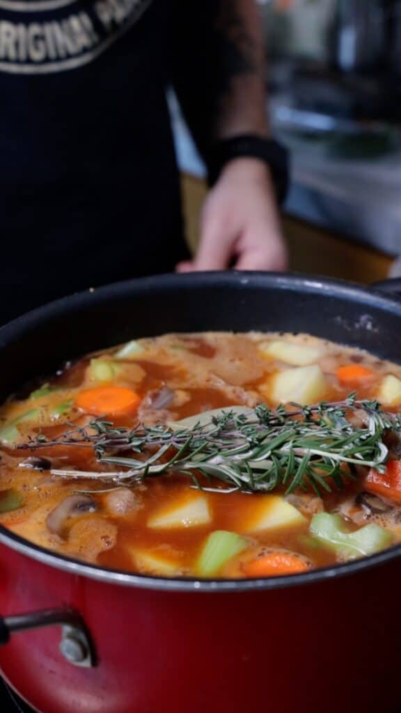 adding fresh thyme and rosemary into the stew
