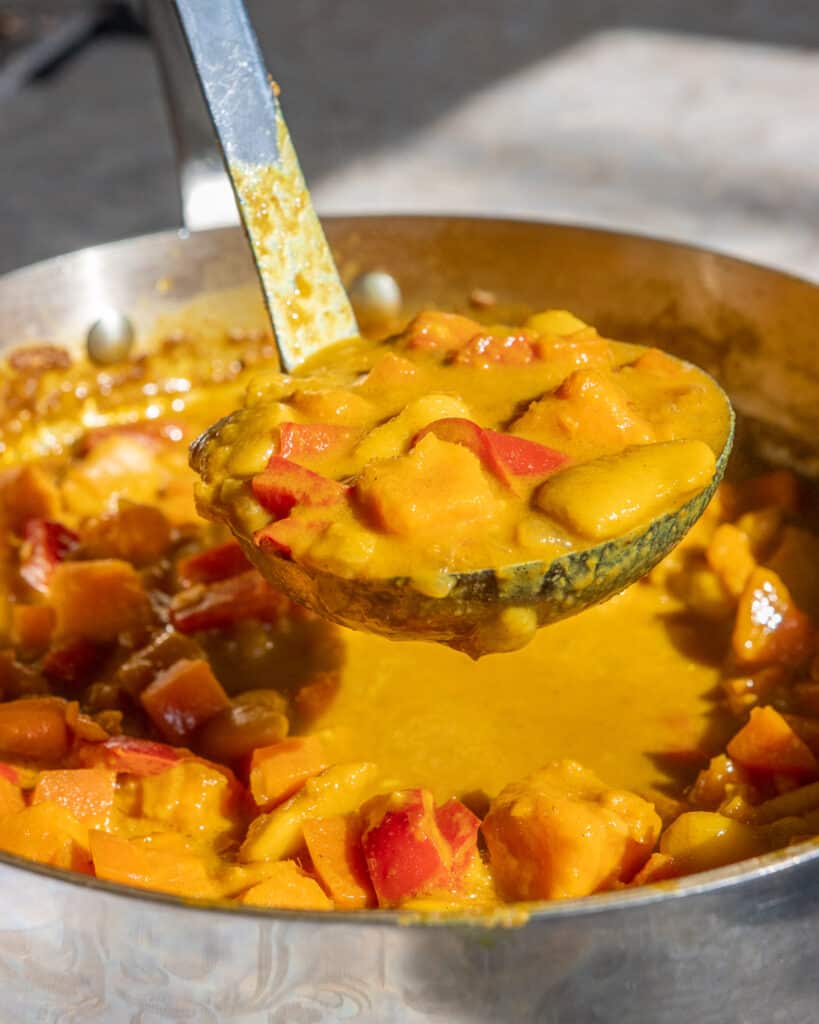 A ladle of Easy Sweet Potato Curry being scooped out of the pot.