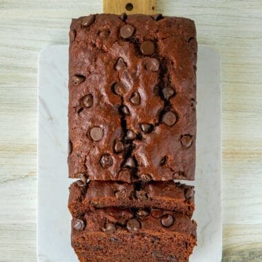 a loaf of double chocolate vegan banana bread sitting sliced on a cutting board