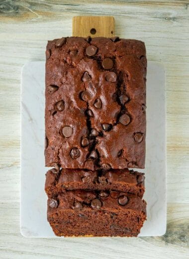 a loaf of double chocolate vegan banana bread sitting sliced on a cutting board