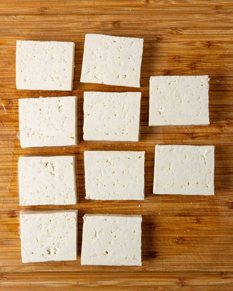 square tofu slices laid out on a wooden cutting board